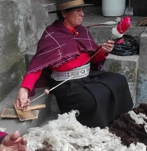 lady spinning w carded wool in foreground